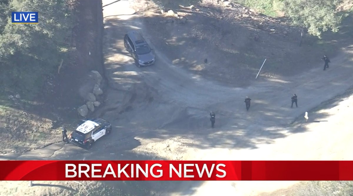 LAPD officers are approaching the pursuit suspect who remains inside of the vehicle