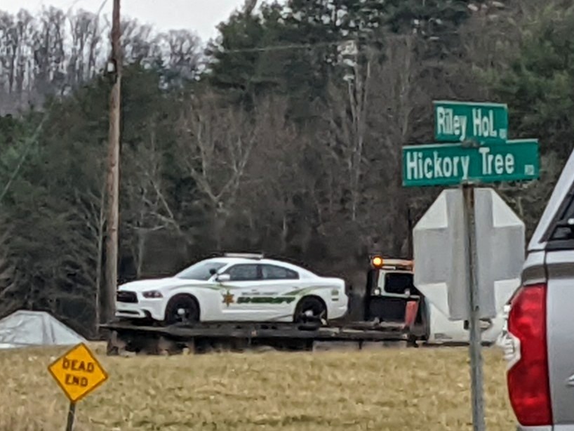 A rollback truck hauls a Sullivan County Sheriff's Office cruiser out of Riley Hollow Rd following a standoff with a potential suspect in a Friday morning shooting that left an officer critically wounded.