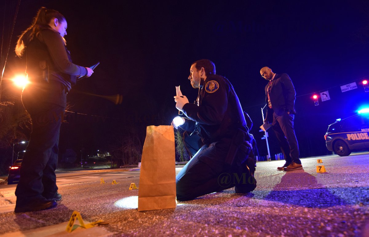 Homicide detective Marcus Smothers watches as crime lab technicians collect more than two dozen pieces of evidence scattered across the intersection of Pimlico Road and Cross Country Boulevard