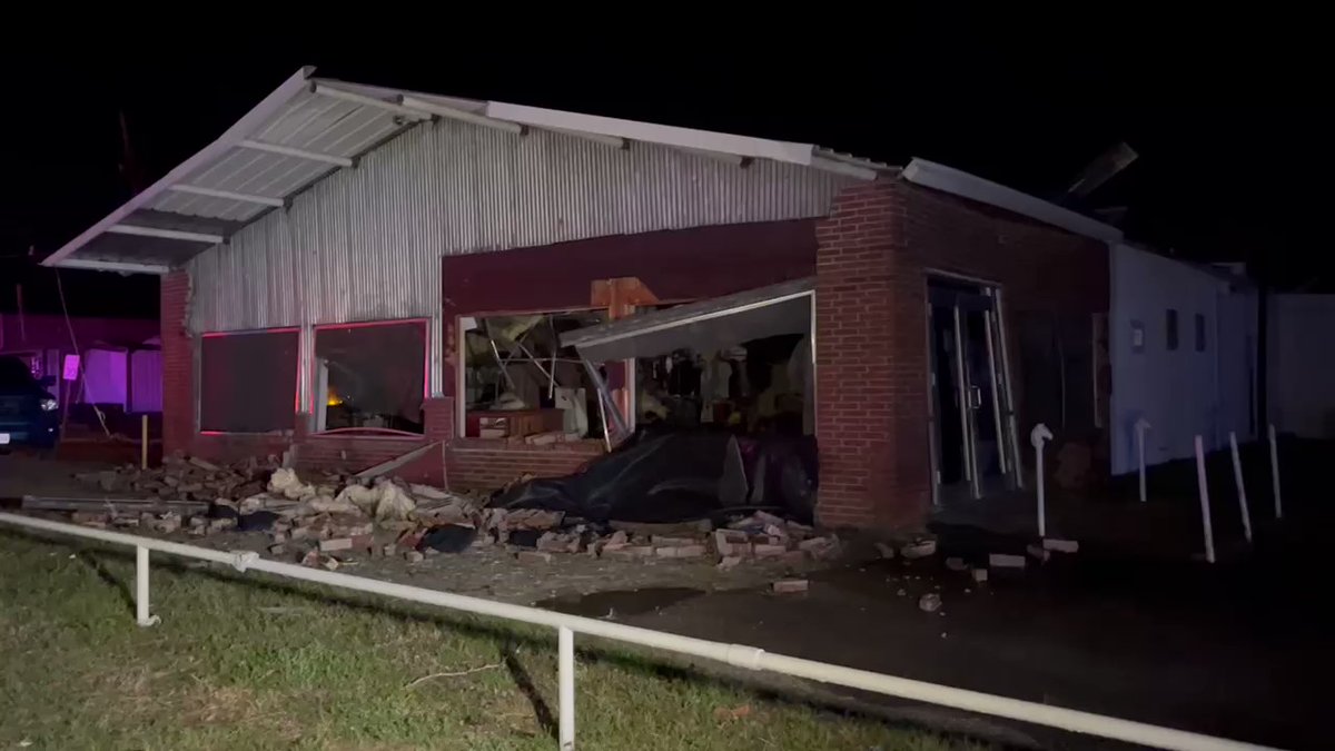 Retail store and barbershop on N May in Madisonville heavily damaged after tornado. Roof pieces and street lights dangle above on mangled wires