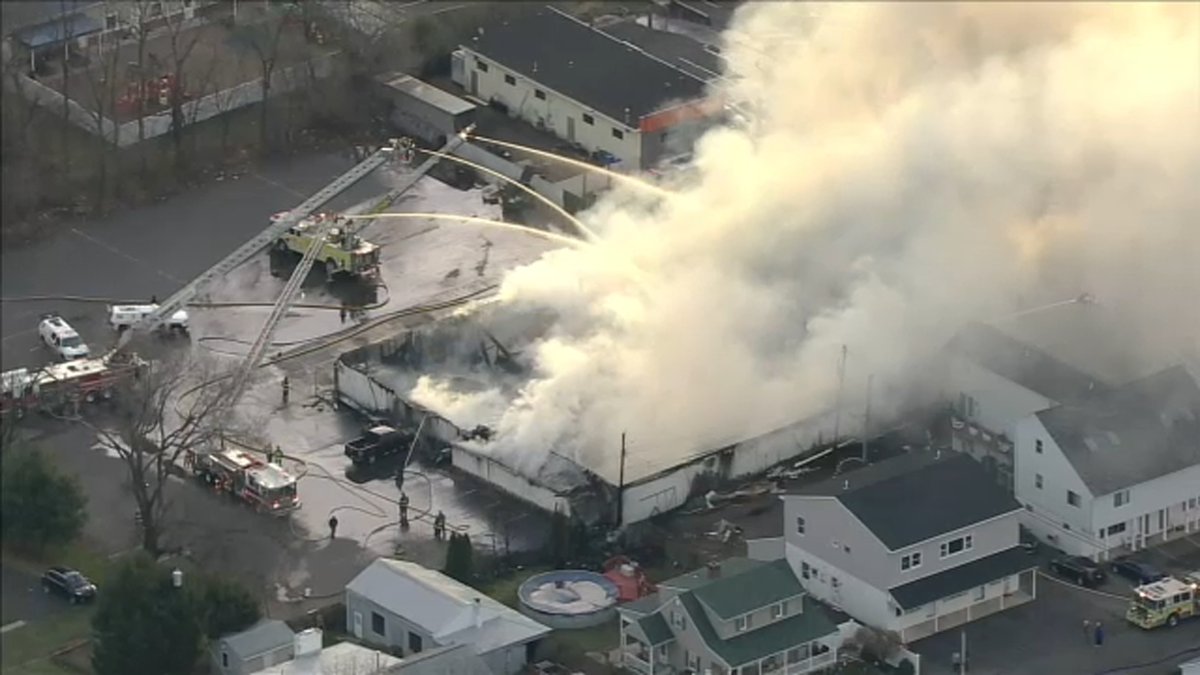 Smoke shoots into the air as crews continue to work on the massive fire at a Bucks County bowling alley