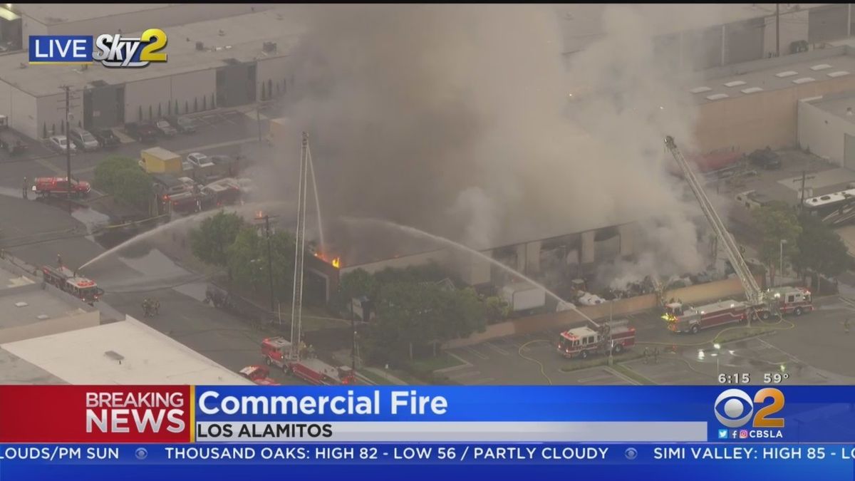 Firefighters make progress against a 2-alarm blaze at a Los Alamitos commercial building, where several cars in the parking lot were also seen burning