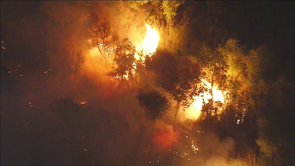Crews continue battling a brush fire burning near homes in Eastvale.
