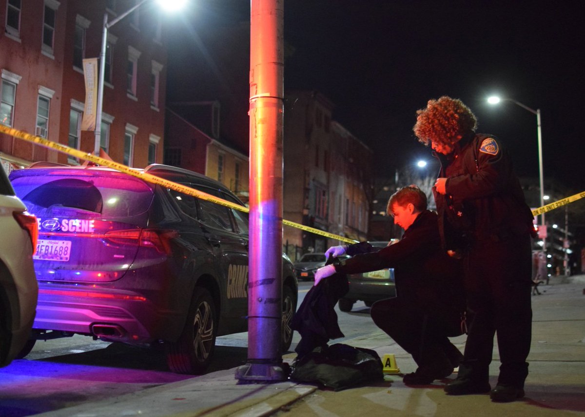 A crime lab technician examines a piece of clothing that was left behind by a 30-year-old man who was found with stab wounds near Lexington Market on Tuesday. Police said the injured man sought help from an officer working in the 300 block of North Eutaw Street