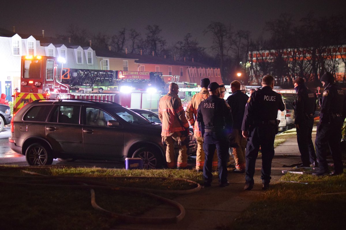 Baltimore County firefighters and police gather in a cluster in front of an apartment unit that caught fire in Parkville on Tuesday. Firefighters rescued two people from the apartment: a man and a baby girl