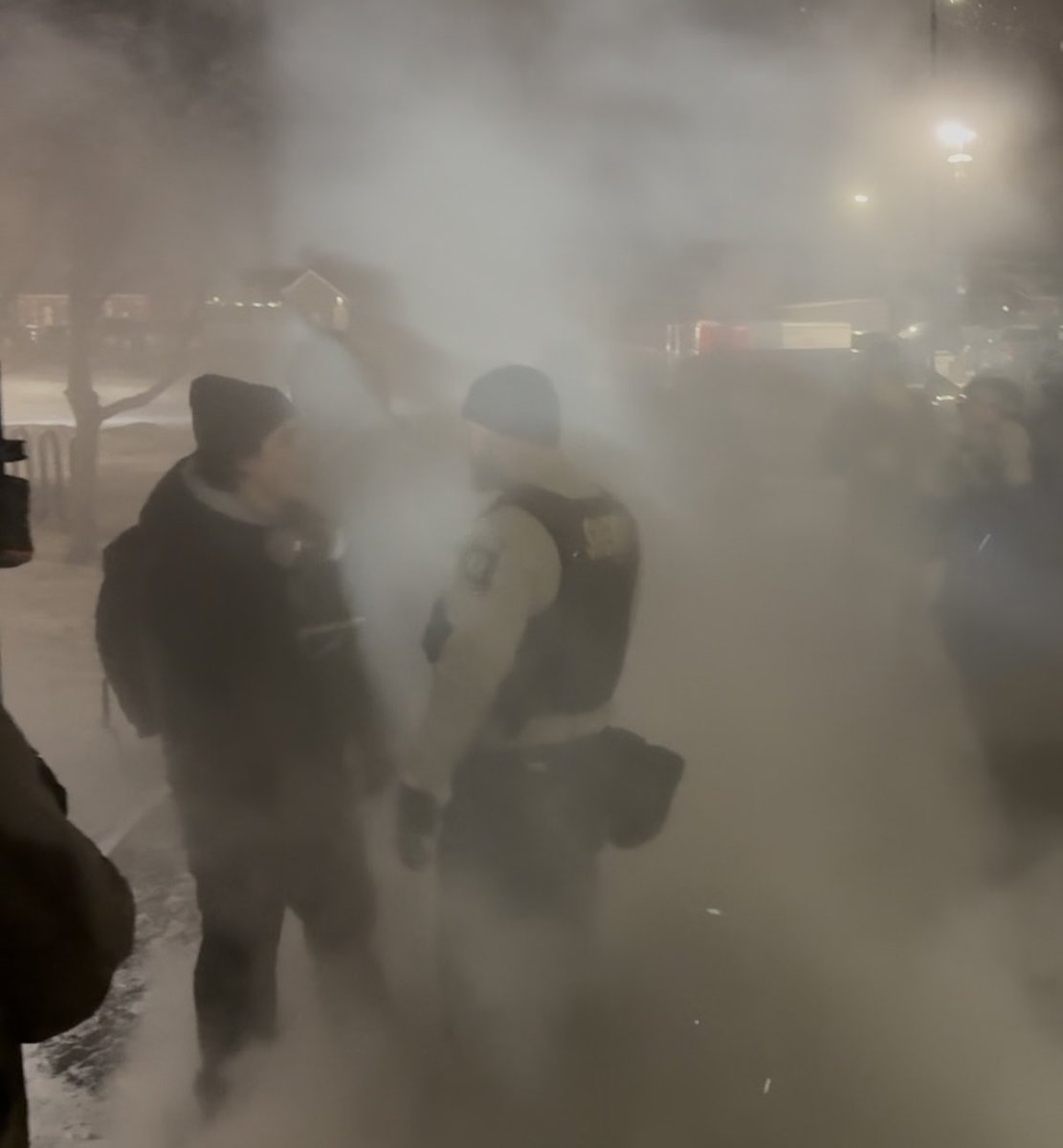 Protester squares off with Hennepin County Sheriffs amidst the smoke from the fires