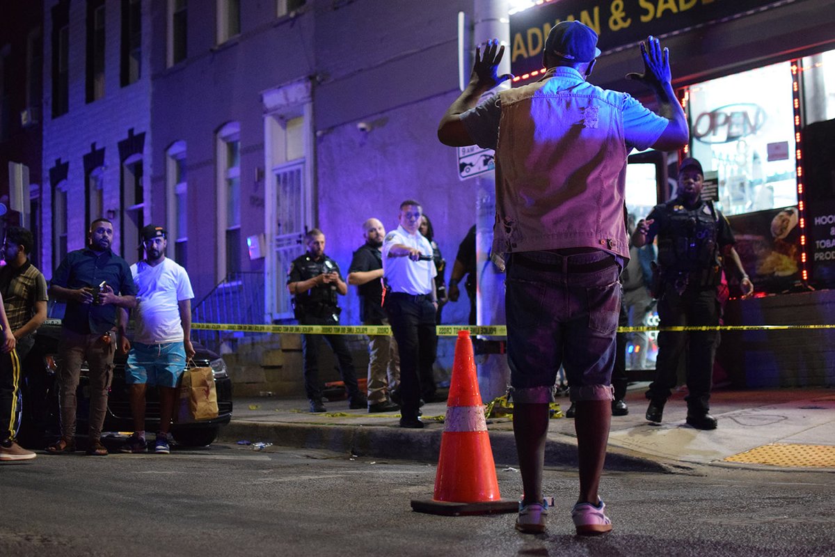 The father of a gunshot victim asks about his son as he approaches an orange cone marking one of several cartridge casings surrounding a corner store in the 1200 block of East Preston Street. Police say a 21-year-old man and 32-year-old man were shot